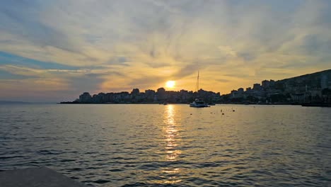 saranda coastal city magical sunset, port and bay, sea glistening, sky painted with vibrant clouds - a spectacular evening scene