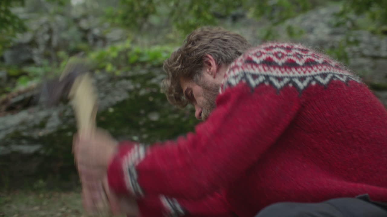Man Chopping Log with Axe on Forest Floor during Camping Trip in Nature