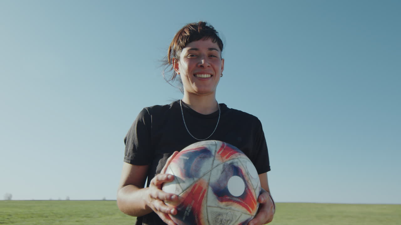 Atleta gioiosa che tiene in mano un pallone da calcio e sorride alla telecamera
