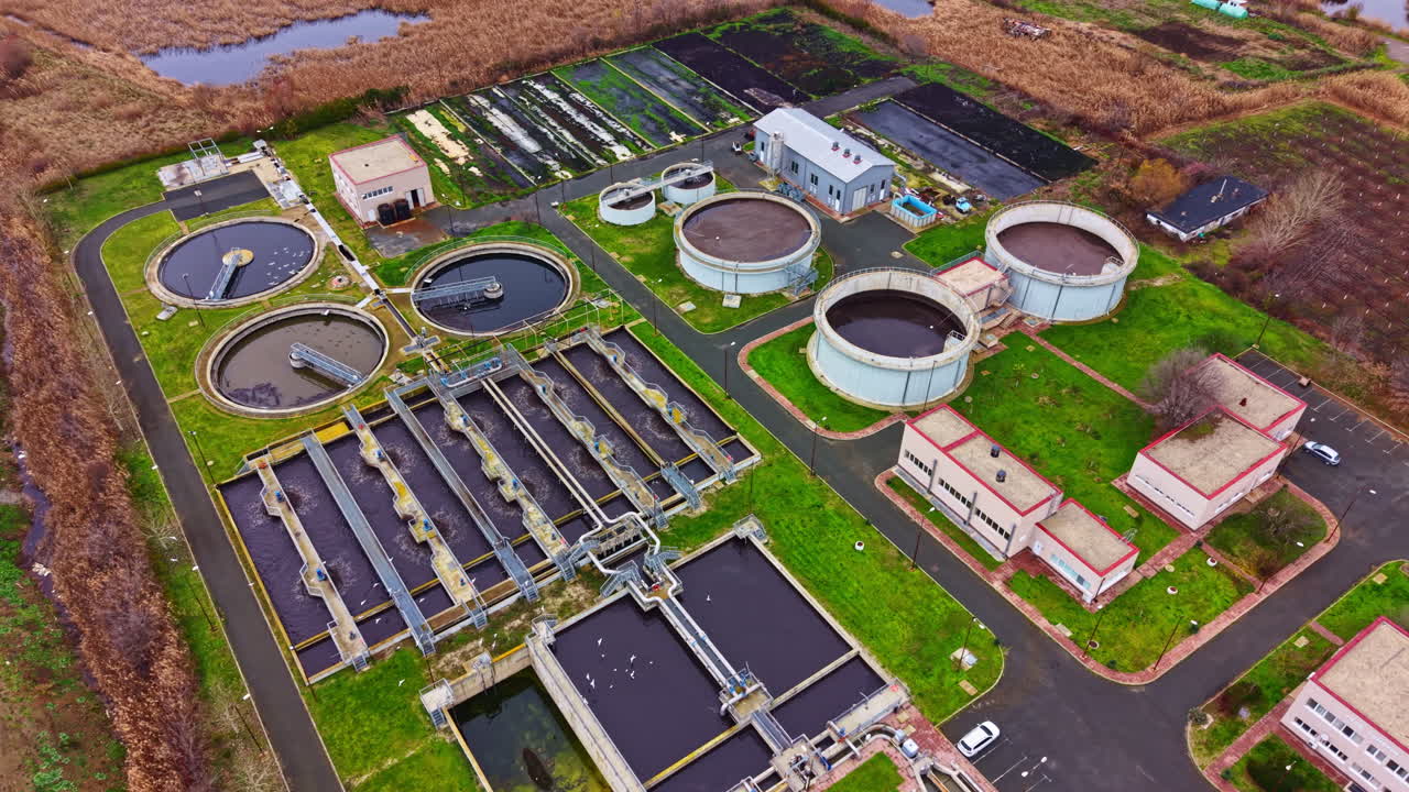Water treatment facility shows various tanks and structures used for processing and cleaning wastewater in a large industrial area