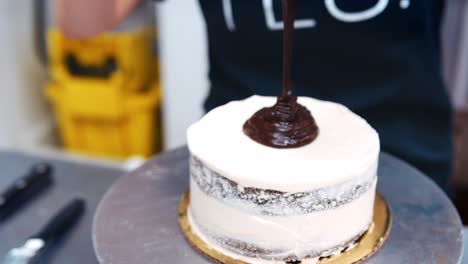 cerca del panadero extendiendo chocolate derretido en el pastel con un cuchillo