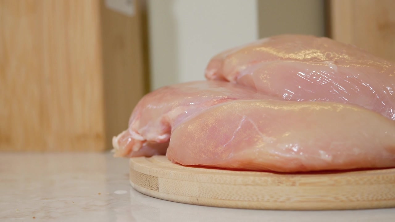 Petti di pollo crudi freschi su un tagliere di legno