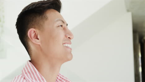 a young asian man smiles brightly at home in a well-lit space, with copy space