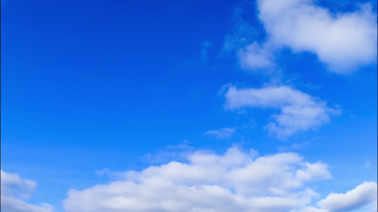 Bright blue sky with soft fluffy cloudscape. White cumulus clouds quickly changing shape in the atmosphere. Low angle view.