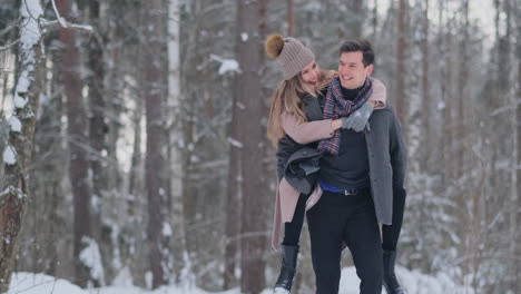 Una-Pareja-Feliz-Está-Jugando-Juegos-De-Invierno-Afuera-Disfrutando-De-La-Luz-Del-Sol-Y-Del-Cálido-Clima-Invernal-En-Las-Montañas.-Un-Chico-Fuerte-Lleva-A-Su-Novia-Sobre-Sus-Hombros-Y-La-Hace-Girar.