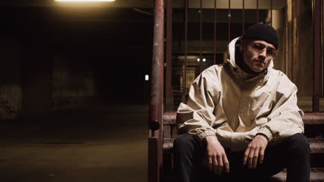 man sitting on stairs in underground parking garage