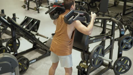 fit mann macht beinübungen in v-leverage squat-maschine im indoor-gymnasium - blick aus hohem winkel