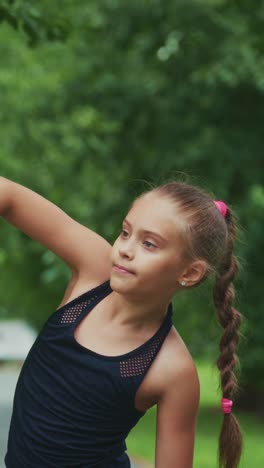 a young girl engages in athletic training, showcasing strength and focus while holding a pink ball in a lush outdoor setting