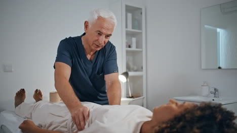 physician examining patient trauma in clinic. mature therapist talking woman