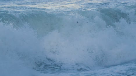 cerca de las olas del mar rompiendo en la playa en cámara lenta con el reflejo del sol en el agua en el fondo. imágenes ásperas del océano durante las condiciones de tormenta en la bahía británica 4k.