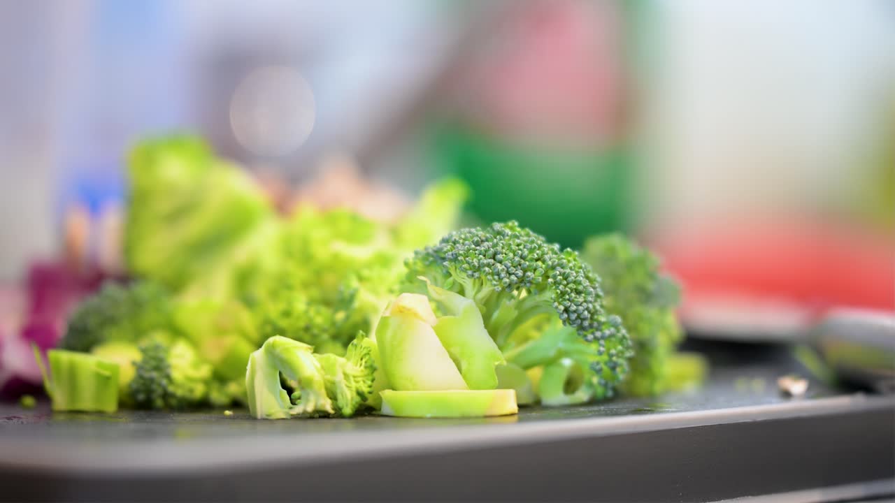 A cinematic close-up with a very shallow depth of field focuses on freshly cut broccoli. Other healthy ingredients, like mushrooms and onions, are beautifully blurred in the background
