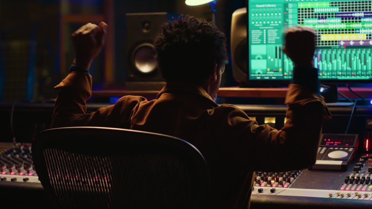 아프리카계 미국인 음악 프로듀서가 프로 스튜디오에서 새로운 트랙을 연주하고 있습니다.