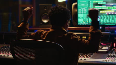 productor de música afroamericano vibrando en su nueva pista en un estudio profesional