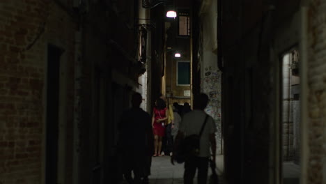 people walking through a narrow alleyway at night in venice