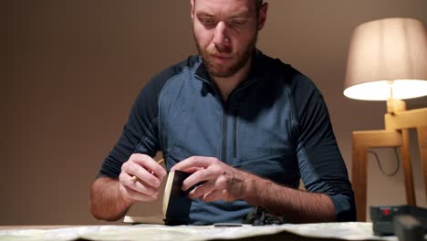 bearded man checking map while calculating route and taking notes for his next expedition