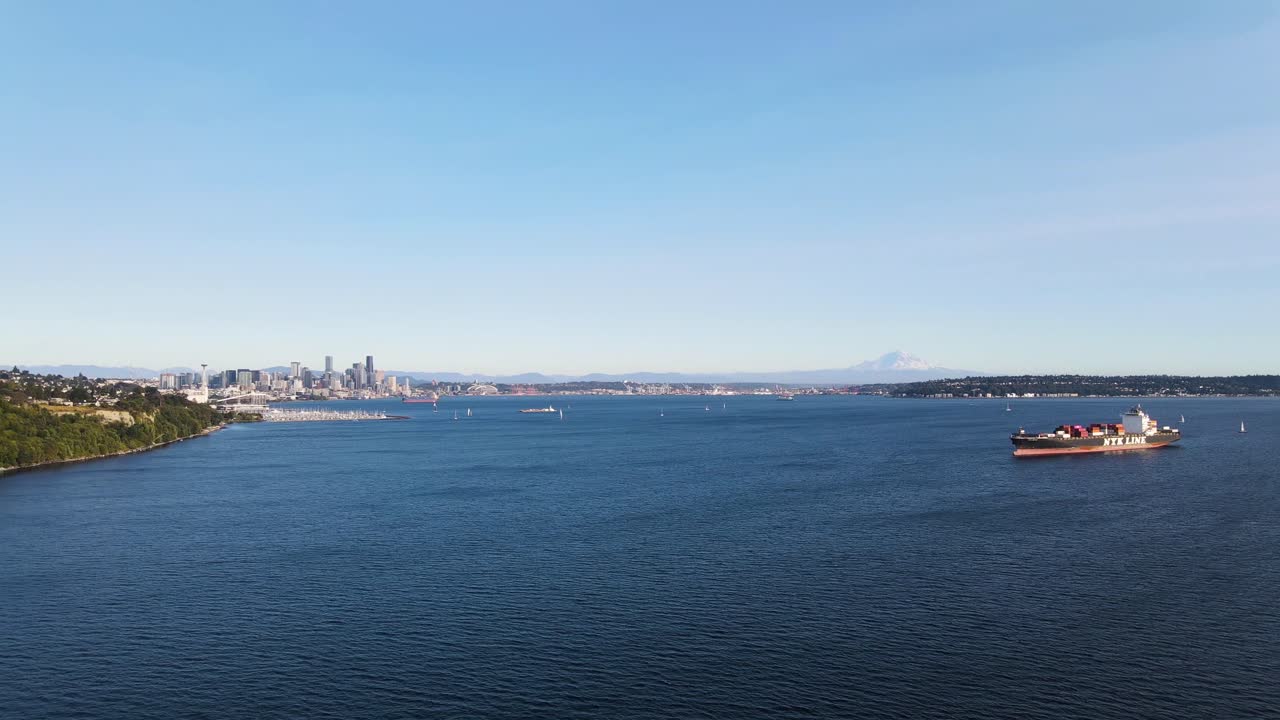 Drone soars above Seattle's coast, revealing the city skyline in the backdrop
