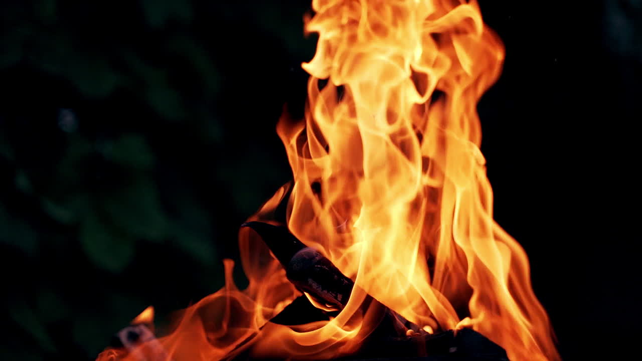 Beautiful fire burns brightly. Burning logs in orange flames. Background of the fire. Red flames surging up. Close-up.