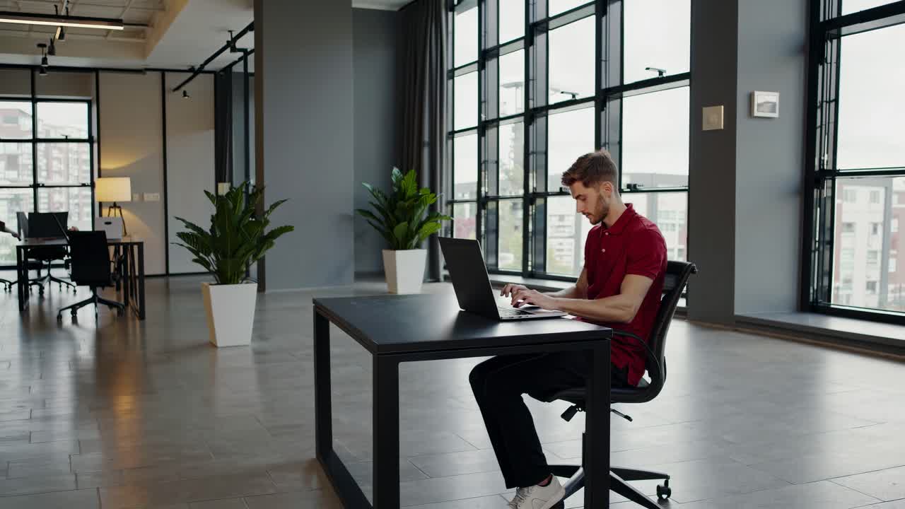 Wide-angle video of a modern office with a man working on a laptop, showcasing a minimalist design