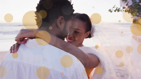animación de puntos de luz sobre una pareja afroamericana casándose en la playa