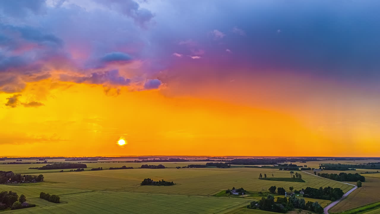 Time-lapse Of A Sun Setting With Dark Cloudscape Over A Rural Landscape
