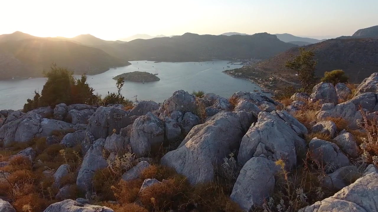Vista panoramica di una baia mediterranea al tramonto da un pendio roccioso