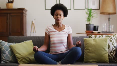 Afroamerikaner-Entspannt-Sich-Auf-Der-Couch,-Sitzt-In-Yoga-Pose-Und-Meditiert