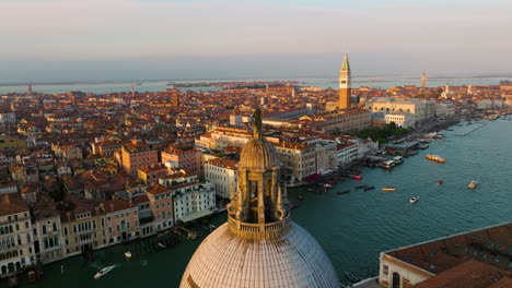 Vista-Aérea-De-Venecia-Y-Gran-Canal-En-La-Basílica-De-Santa-Maria-Della-Salute-Al-Atardecer-En-Italia---Disparo-De-Drones