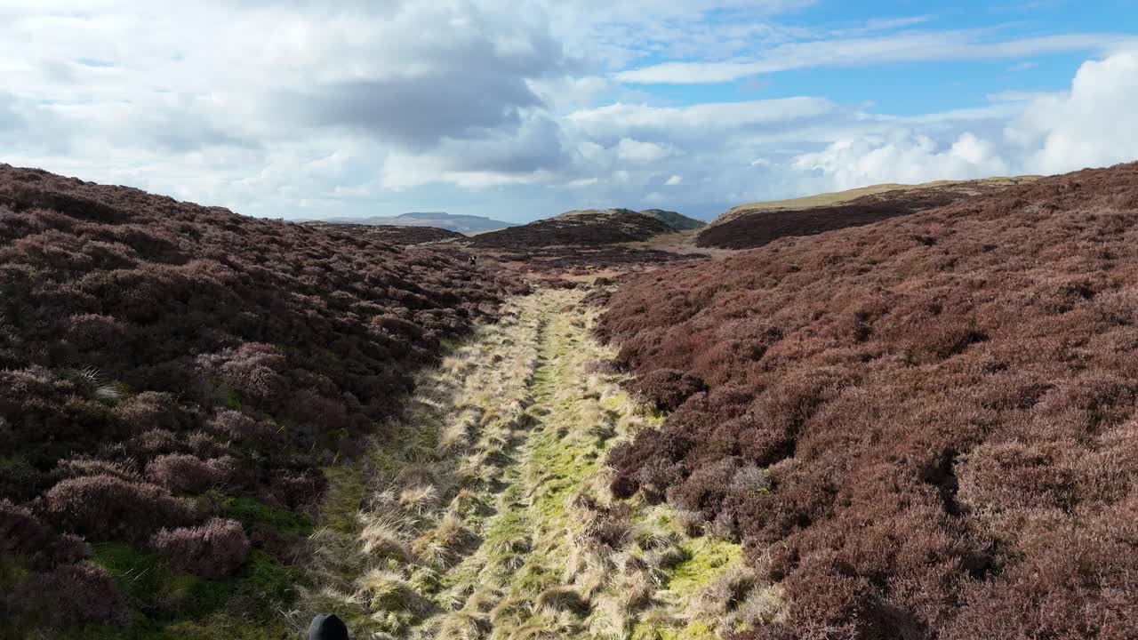 hombre corriendo en una colina en escocia durante la temporada de primavera en un día despejado