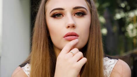 Medium-shot-of-a-beautiful-women-sitting-in-a-garden-and-staring-into-the-camera-playing-seductively-with-her-lips-and-flirting