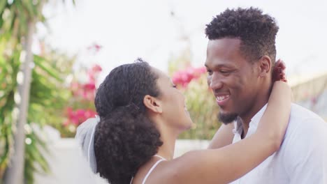 happy married african american couple embracing and wearing wedding clothes