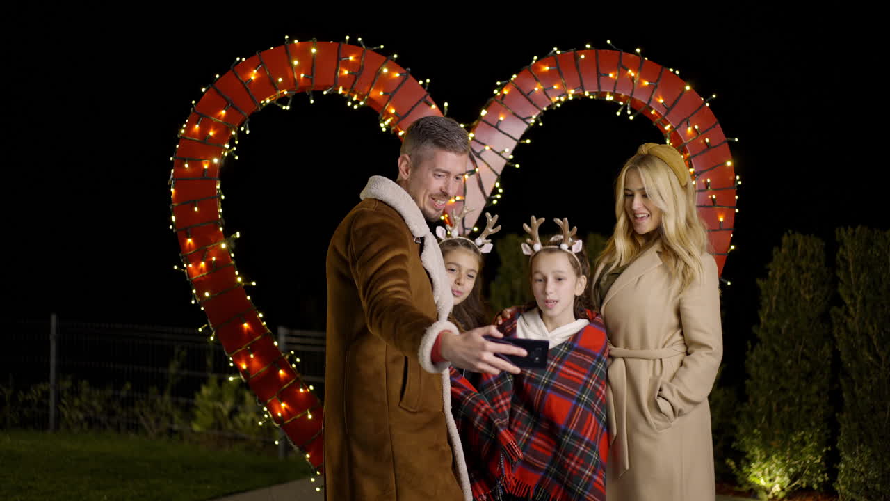 Family Taking Selfie in Front of Heart-Shaped Lights