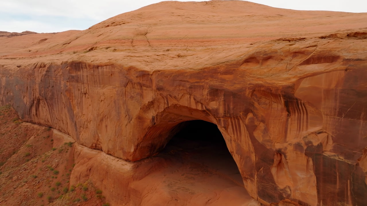 Aerial View Red Sandstone Cave Opening In Remote Red Rock Canyon, Sweeping Cliff Face With Layered Strata,