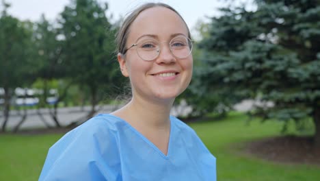 Young-Nurse-Takes-off-Covid-Mask-Outside-in-a-City-Park-Smiling-with-a-Close-Up-Slow-Motion-Shot