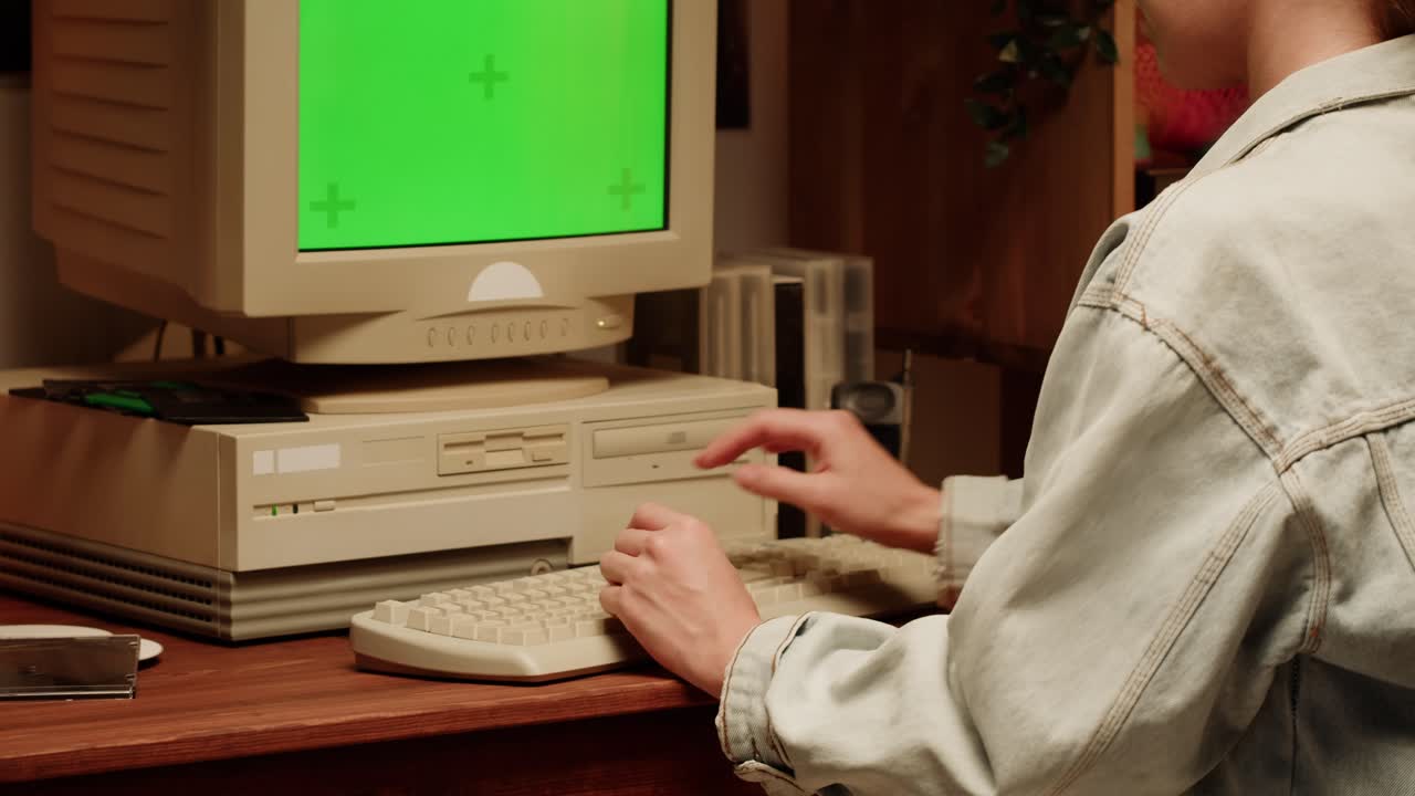 Woman using a vintage computer with green screen monitor.