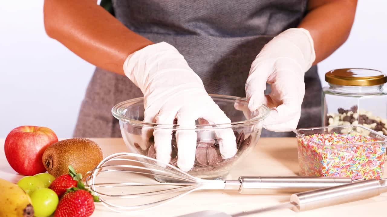 manos con guantes preparando discos de chocolate con ingredientes