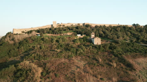 Freizügige-Aufnahme-Der-Burg-Obidos-Hinter-Einer-Mauer-In-Portugal-Mit-Ermida-De-Nossa-Senhora-Do-Carmo-Kapelle-Im-Vordergrund---Aufsteigender-Dröhner,-Weitwinkelaufnahme