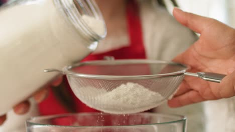 close up of woman sifting flour through sieve