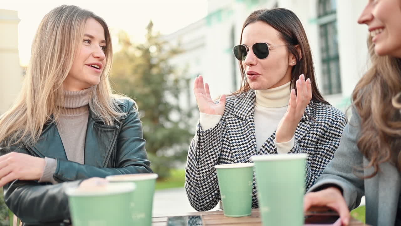 Three women talking and drinking coffee at a terrace