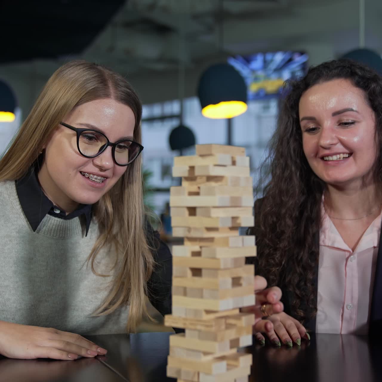 Break from work in the office. Office staff having fun and relax playing jenga at lunch break time. Blurred background