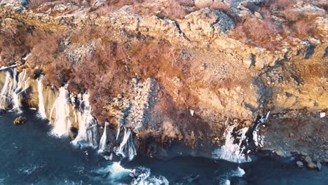 Drone-with-cinematic-movements-shows-beautiful-icelandic-waterfall,-Hraunfossar,-in-sunset-light-from-multiple-angles