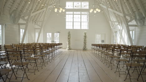 rustic bright white barn wedding venue interior with aisle and chairs