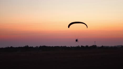 El-Piloto-De-Un-Parapente-Vuela-En-El-Cielo-Después-Del-Atardecer-Con-Naranja.-Fondo