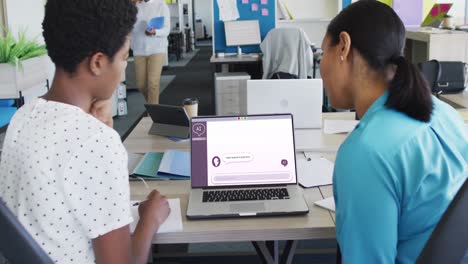 mujeres de negocios diversas que usan computadoras portátiles con procesamiento de datos en la pantalla en la oficina