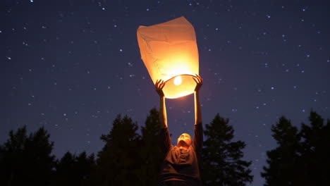 person releasing a sky lantern at night