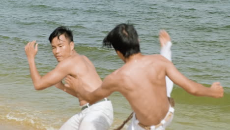 dos hombres bailando capoeira en la playa