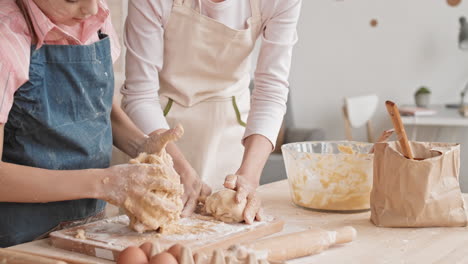 caucasian girl kneading dough together with her mom