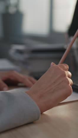 person writing on paper at a desk