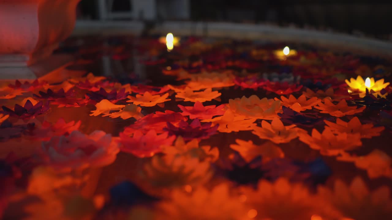 Colorful flowers and candles rotating in a pool under dim light.Such a tranquil scene