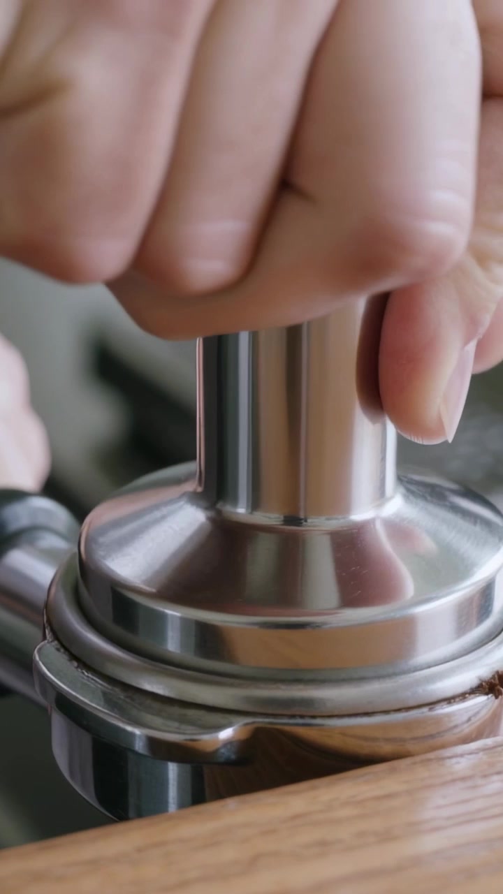 Vertikales Video: Nach dem Dosieren für Espresso pressen Hände den Tamper zu Hause in den Siebträger