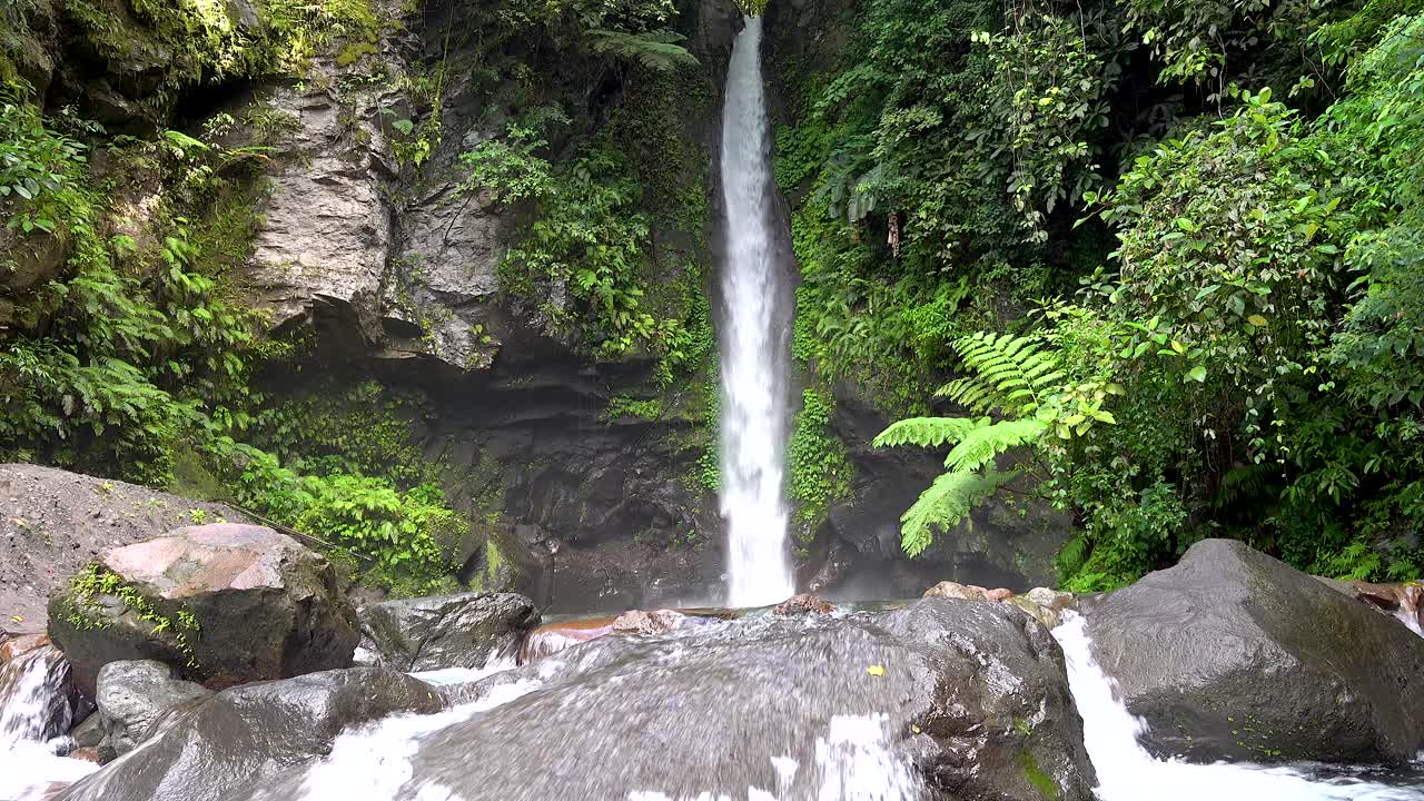 waterfall surrounded by lush green vegetation big rocks and boulders on a topical island rainforest